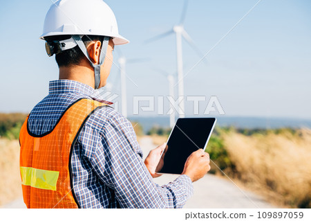 Technician with tablet at windmill farm. Engineer ensures clean energy. Expertise in turbine efficiency global electricity control and innovation portrayed confidently. Technician with tablet at windmill farm. Engineer ensures clean energy. Expertise in turbine efficiency global electricity control and innovation portrayed confidently. 109897059
