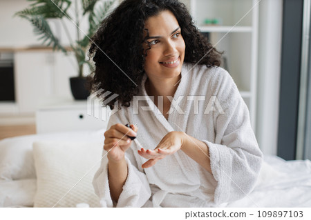 Portrait of female in white bathrobe making manicure Portrait of female in white bathrobe making manicure 109897103