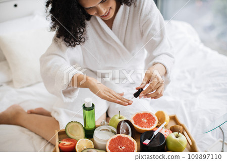 Top view of hands of lady in dressing gown, paints nails Top view of hands of lady in dressing gown, paints nails 109897110