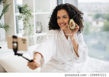 Portrait of young multinational woman holding half of avocado, skin care concept Portrait of young multinational woman holding half of avocado, skin care concept 109897221