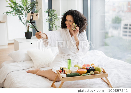 Beautiful young African woman social media influencer holding half of avocado 109897241