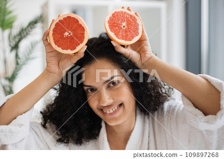 Smiling African female after bath holding two halves of grapefruit on top hair 109897268