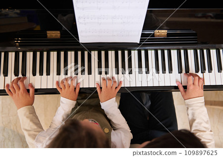 Top view of children hands on piano keyboard, touching white and black keys while playing music on grand piano 109897625