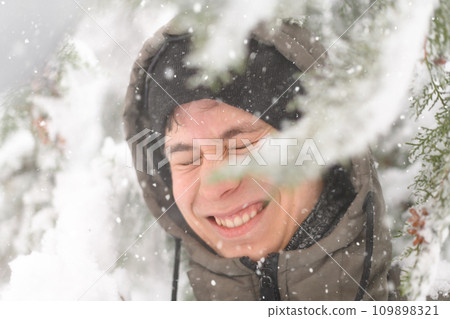 a boy is playing with snow on the street, it is snowing, a blizzard and frost on a winter day a boy is playing with snow on the street, it is snowing, a blizzard and frost on a winter day 109898321