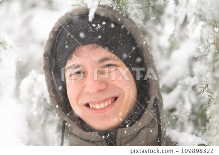 a boy is playing with snow on the street, it is snowing, a blizzard and frost on a winter day 109898322