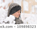 a boy is playing with snow on the street, it is snowing, a blizzard and frost on a winter day 109898323