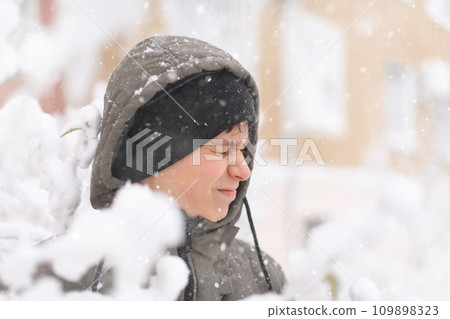 a boy is playing with snow on the street, it is snowing, a blizzard and frost on a winter day a boy is playing with snow on the street, it is snowing, a blizzard and frost on a winter day 109898323