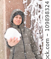 a boy is playing with snow on the street, it is snowing, a blizzard and frost on a winter day 109898324