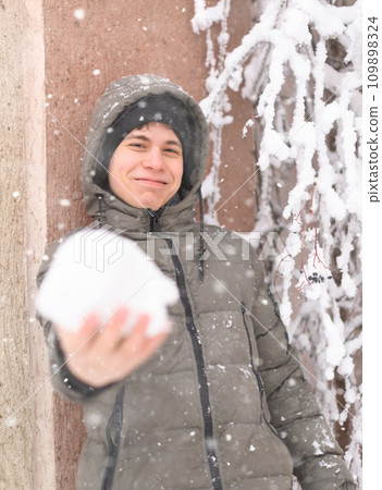 a boy is playing with snow on the street, it is snowing, a blizzard and frost on a winter day 109898324