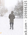 A boy walks along a snowy street, it is snowing, blizzard and frost on a winter day 109898325