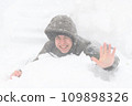 a boy lies in the snow, on a snowy street, it is snowing, a blizzard and frost on a winter day 109898326