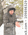 a boy is posing with snow on the street, it is snowing, a blizzard and frost on a winter day 109898329