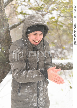 a boy is posing with snow on the street, it is snowing, a blizzard and frost on a winter day 109898329