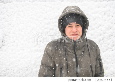 a boy is posing on snow background outdoor, it is snowing, a blizzard and frost on a winter day a boy is posing on snow background outdoor, it is snowing, a blizzard and frost on a winter day 109898331