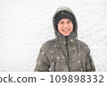 a boy is posing on snow background outdoor, it is snowing, a blizzard and frost on a winter day 109898332