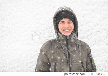 a boy is posing on snow background outdoor, it is snowing, a blizzard and frost on a winter day a boy is posing on snow background outdoor, it is snowing, a blizzard and frost on a winter day 109898332