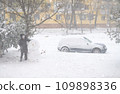 a girl is playing with snow on the street, making snowman, it is snowing, a blizzard and frost on a winter day 109898336