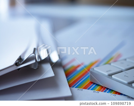Graphs, documents and a keyboard on the table 109898719