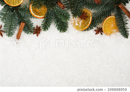 Christmas white snow background with fir tree, dried orange, cinnamons and star anise. Copy space for your text Christmas white snow background with fir tree, dried orange, cinnamons and star anise. Copy space for your text 109898950