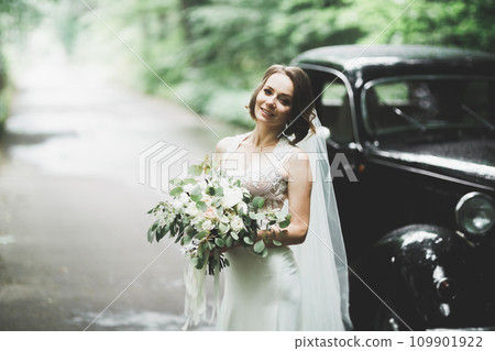 Gorgeous elegant bride posing near stylish retro black car Luxury wedding in vintage style. Portrait 109901922