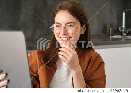 Portrait of young woman, student studying on remote, using digital tablet to study online course, e-learning, working from home in kitchen Portrait of young woman, student studying on remote, using digital tablet to study online course, e-learning, working from home in kitchen 109902449