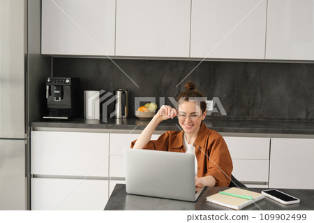 Portrait of woman freelancer, programmer working from home. Female student or business owner sitting with laptop in kitchen Portrait of woman freelancer, programmer working from home. Female student or business owner sitting with laptop in kitchen 109902499