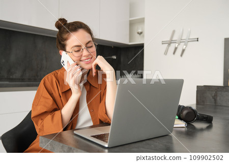 Portrait of woman working or studying at home, using laptop and mobile phone Portrait of woman working or studying at home, using laptop and mobile phone 109902502