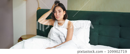 Portrait of sad young woman waking up, feeling bad, wants to sleep, wakes early morning, looking lazy and upset Portrait of sad young woman waking up, feeling bad, wants to sleep, wakes early morning, looking lazy and upset 109902719