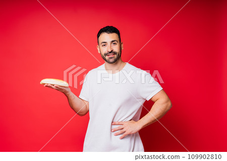 Man holding freshly baked bread in hands isolated on red background Man holding freshly baked bread in hands isolated on red background 109902810