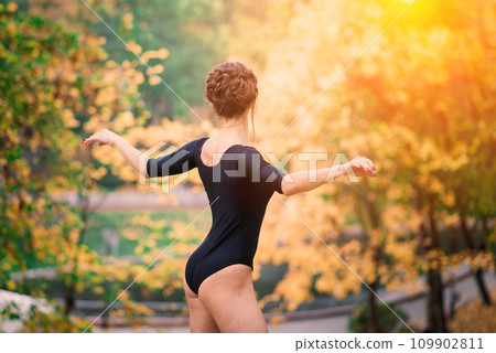 Beautiful female, ballerina, athlete in black bodysuit training in the park Beautiful female, ballerina, athlete in black bodysuit training in the park 109902811