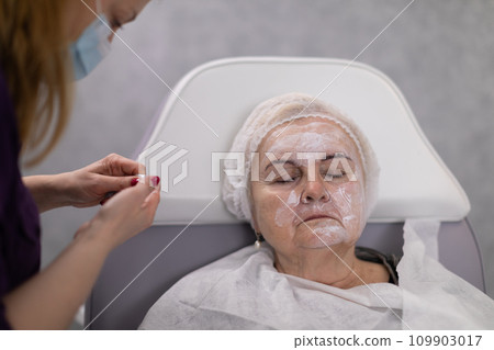 A beautician takes care of a beauty salon client by caring for her face. A beautician takes care of a beauty salon client by caring for her face. 109903017