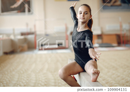 Child gymnastics balance beam. Girl gymnast athlete during an exercise horizontal bar in gymnastics competitions. 109904131