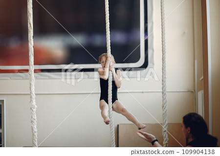 Coach with student. Girls gymnasts, performs various gymnastic exercises and jumping. Childs and sport, a healthy lifestyle. Coach with student. Girls gymnasts, performs various gymnastic exercises and jumping. Childs and sport, a healthy lifestyle. 109904138