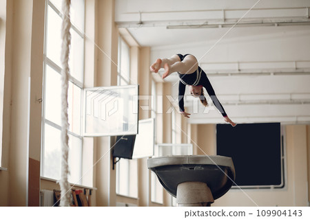 Child gymnastics balance beam. Girl gymnast athlete during an exercise horizontal bar in gymnastics competitions. Child gymnastics balance beam. Girl gymnast athlete during an exercise horizontal bar in gymnastics competitions. 109904143