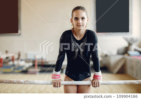 Child gymnastics balance beam. Girl gymnast athlete during an exercise horizontal bar in gymnastics competitions. Child gymnastics balance beam. Girl gymnast athlete during an exercise horizontal bar in gymnastics competitions. 109904166
