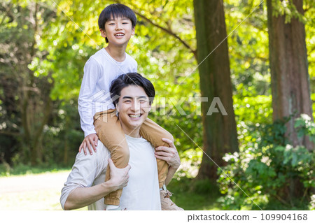A father who carries his child on his shoulders A father who is active in childcare A father who carries his child on his shoulders A father who is active in childcare 109904168