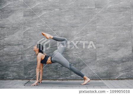 Pretty lady training in a summer city. Brunette doing yoga. Gitl in a sportsuit 109905038