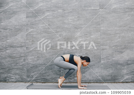 Pretty lady training in a summer city. Brunette doing yoga. Gitl in a sportsuit Pretty lady training in a summer city. Brunette doing yoga. Gitl in a sportsuit 109905039