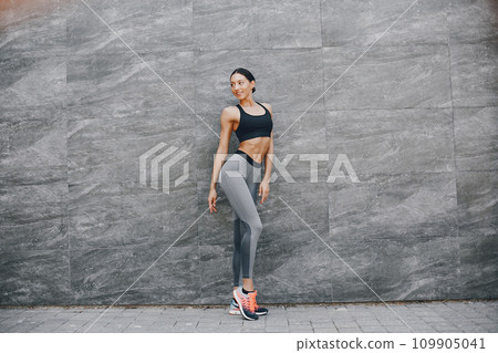Pretty lady training in a summer city. Brunette doing yoga. Gitl in a sportsuit 109905041