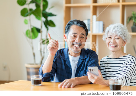 一對年長夫婦一起看他們的智慧型手機。 一對年長夫婦一起看他們的智慧型手機。 109905475