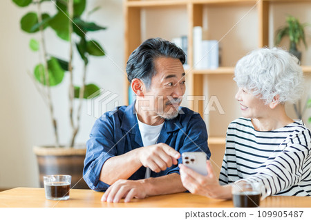 一對年長夫婦一起看他們的智慧型手機。 一對年長夫婦一起看他們的智慧型手機。 109905487