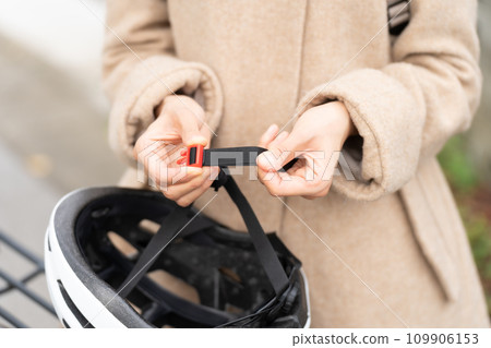 Young woman adjusting the length of the chin strap of her cycling helmet Young woman adjusting the length of the chin strap of her cycling helmet 109906153