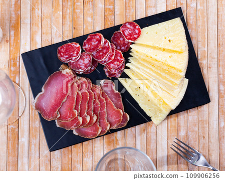 Botifarra, ham and cheese cut into pieces and served in a plate 109906256