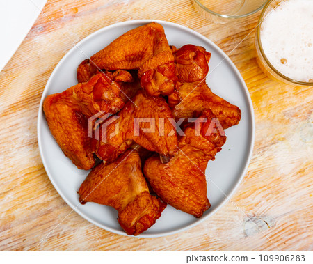 Appetizing smoked chicken wings dished up in a plate on laid restaurant table 109906283
