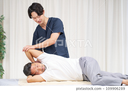 一位年輕的脊椎按摩師正在為一名男子進行治療 一位年輕的脊椎按摩師正在為一名男子進行治療 109906289