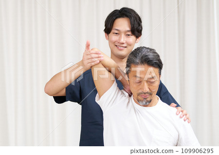 Anma massage shiatsu therapist performing treatment on an elderly man 109906295