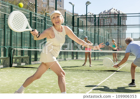 Old woman looking back after the ball while playing Padel Tennis in tennis court Old woman looking back after the ball while playing Padel Tennis in tennis court 109906353