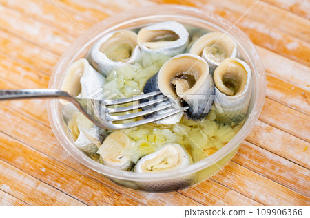 Herring served in plastic container on the table 109906366