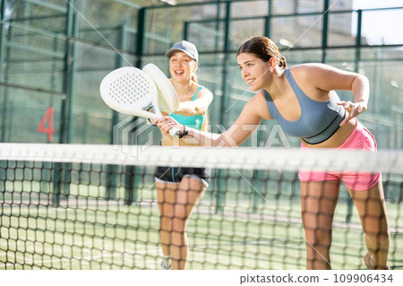 Young women playing Padel Tennis in open-air tennis court Young women playing Padel Tennis in open-air tennis court 109906434