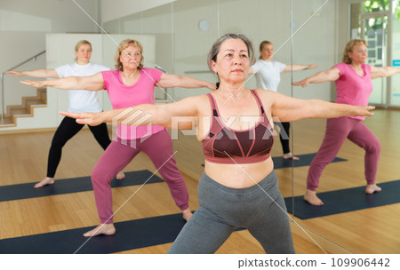 Ladies are doing warrior II pose Ladies are doing warrior II pose 109906442